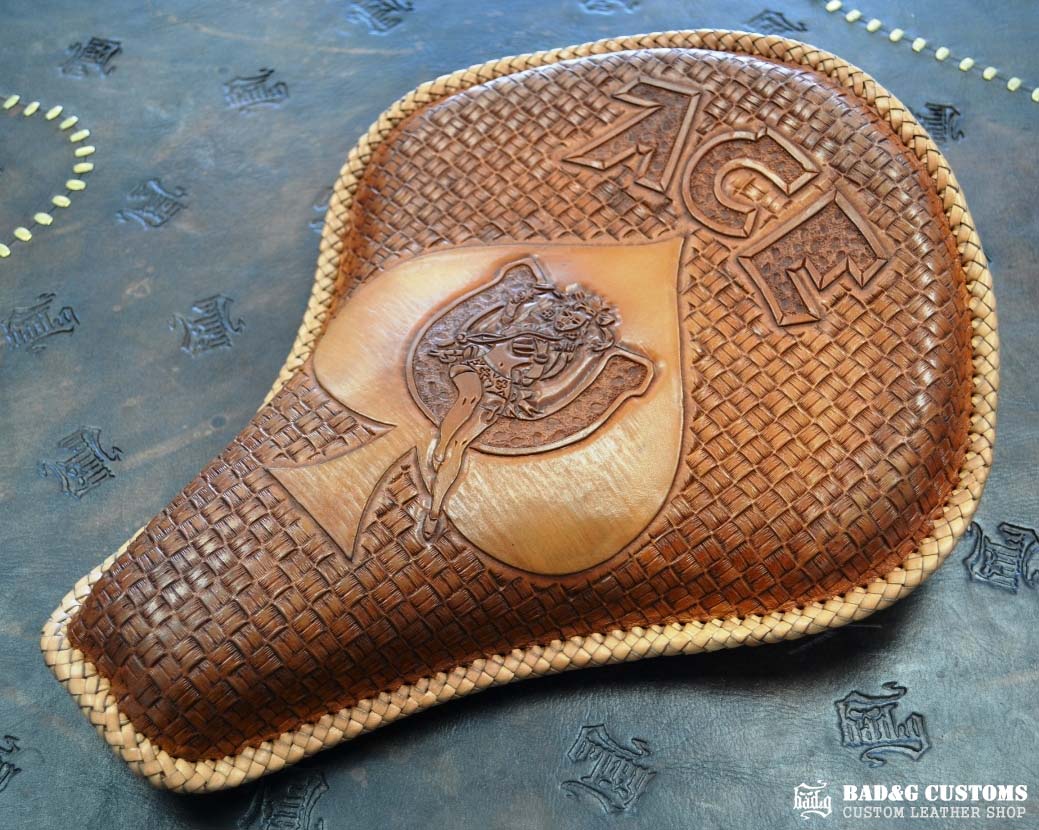 "ACE Pin-Up Girl" design hand tooled and braided on a chopper solo seat. Veg tan leather with kangaroo lace.